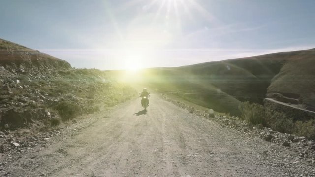 Riding motorcycle along a dirt road inside the mountains. Slow motion	