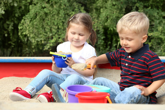 Cute little children playing in  sandbox, outdoors