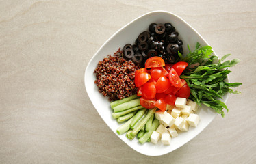 Plate with quinoa and vegetables on light background