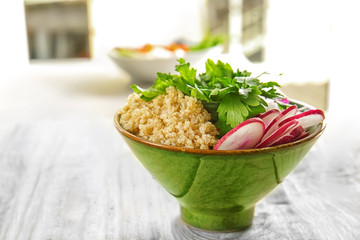 Bowl with quinoa and vegetables on wooden table