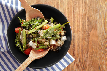 Mixing quinoa salad on wooden background