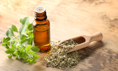 Glass bottle with oregano oil and dried seasoning on table