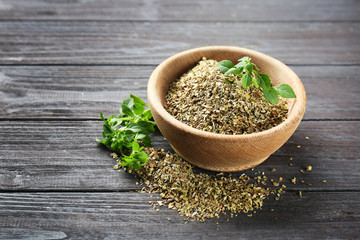 Bowl with dried oregano on wooden table
