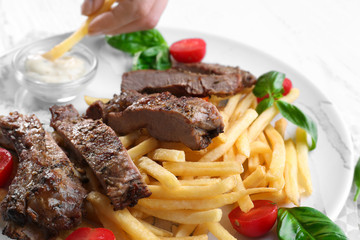 Plate with delicious grilled steak frites on kitchen table
