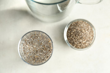 Glass of water and bowl with chia seeds on table