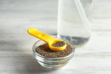 Measuring spoon and bowl with chia seeds on table