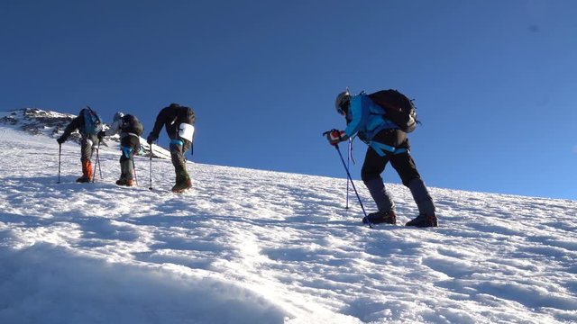 Four Climbers in crampons coming up to the summit of Elbrus. Snow peak.