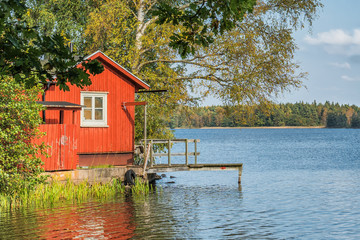 Fototapeta na wymiar Picture of red wooden scandinavian style house at the lake during autumn