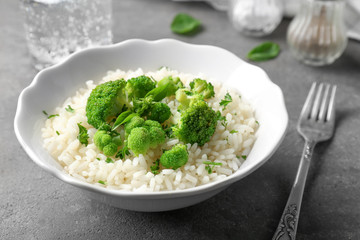 Bowl with rice and broccoli on table