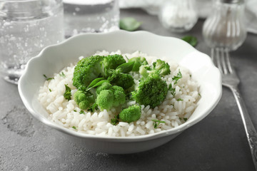 Bowl with rice and broccoli on table