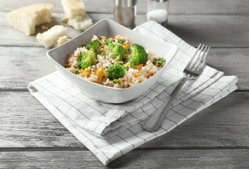Delicious rice pilaf with broccoli in bowl on table