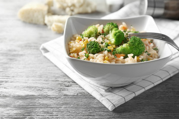 Delicious rice pilaf with broccoli in bowl on table