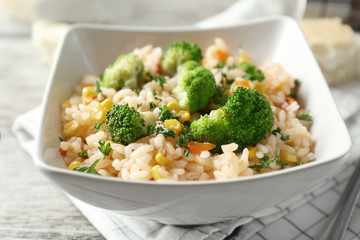 Delicious rice pilaf with broccoli in bowl on table