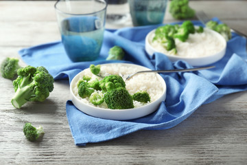 Plate with rice and broccoli on wooden table