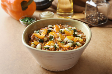 Bowl with tasty brown rice and vegetables on table