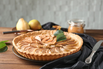 Plate with tasty pear tart on wooden table