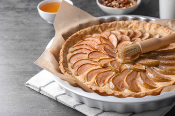 Baking dish with tasty pear tart on table