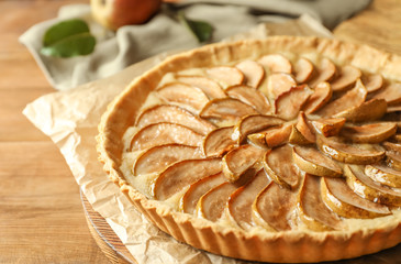 Wooden board with tasty pear tart on table