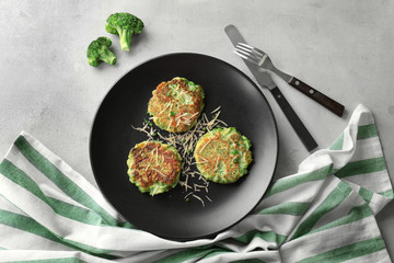 Plate with delicious broccoli pancakes on table