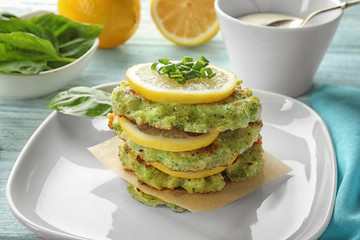 Plate with delicious broccoli pancakes on table