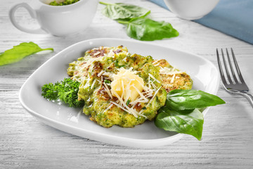 Plate with delicious broccoli pancakes on table