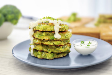 Plate with delicious broccoli pancakes on table
