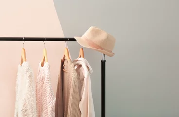 Fotobehang Apricot and beige clothes on hangers against trendy color background © Africa Studio
