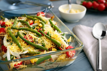 Baking dish with yummy green bean casserole on wooden table