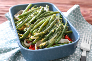 Baking dish with yummy green bean casserole on kitchen table