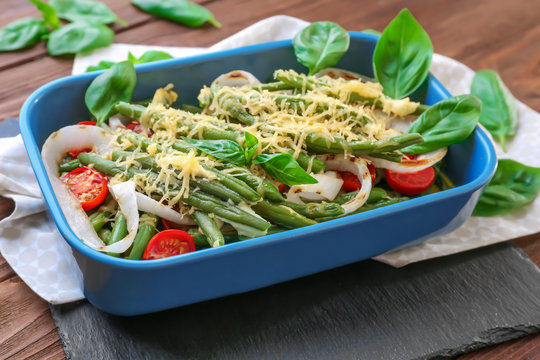 Baking dish with yummy green bean casserole on wooden table