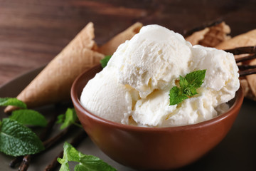 Bowl with yummy vanilla ice cream on table