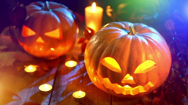 Halloween pumpkin head jack lantern with burning candles over wooden background. Full HD video 1920X1080
