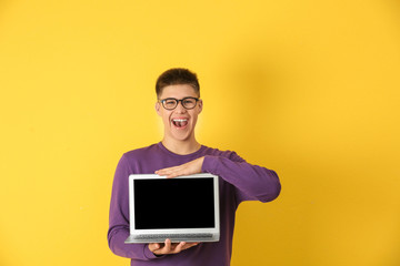 Teenager boy with laptop on color background