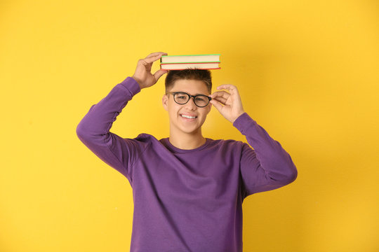 Teenager Boy With Books On Color Background