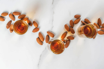 Golden almond liqueur with nuts on white marble background. top view copy space