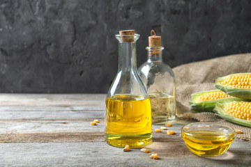 Glassware with corn oil on table against grey background