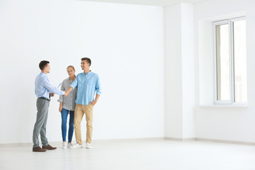 Male realtor and young couple buying new flat