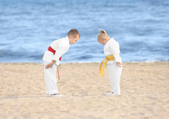 Little children performing ritual bow prior to practicing karate outdoors - obrazy, fototapety, plakaty