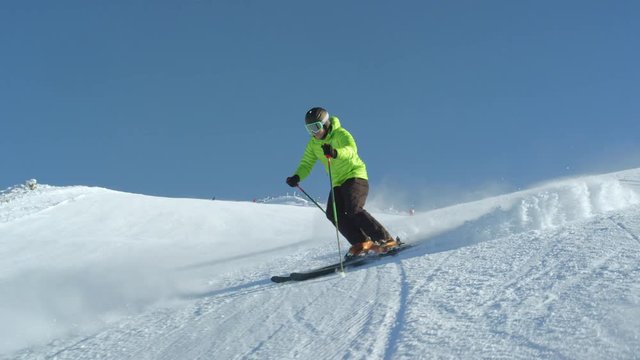 TRACKING SLOW MOTION Amateur skier enjoys idyllic perfect weather on a winter day for recreation skiing down the fresh groomed piste. Modern large ski resort located in Slovenia, Alps, Europe.