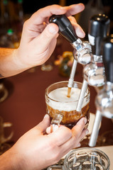 Fototapeta na wymiar Bartender hands pouring a draught craft beer into a mug