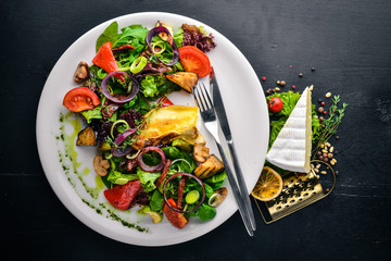 Brie cheese with grilled vegetables. Top view. Free space for text. On a wooden background.