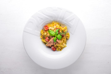 Pasta with tomatoes and basil. Plate with the word "paste". Top view. Free space for text. On a wooden background.