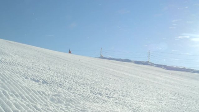 SLOW MOTION CLOSE Young adult skier in bright green jacket carving fast on excellent groomed ski piste in sunny winter day while doing fast slalom turns down the slope. Passing close to the camera