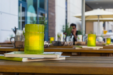 Fototapeta premium Green Glass Candle Restaurant Table Depth of Field Daytime Outdoors