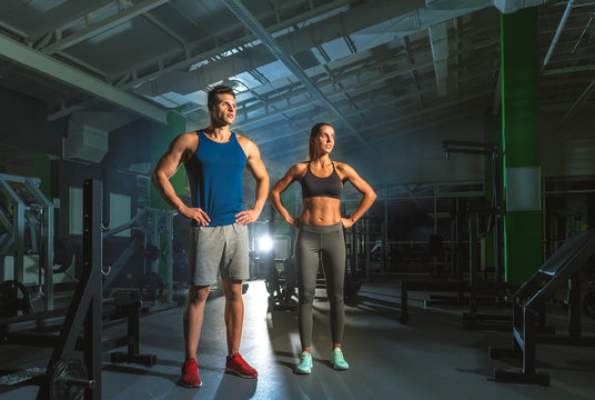 The sport couple stand in the gym on the bright light background