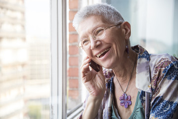 Smiling senior elderly lady having a pleasant conversation over her phone - Powered by Adobe