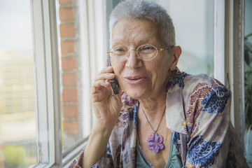 Smiling senior elderly lady having a pleasant conversation over her phone