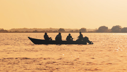Landscape at sunset of a boat with fishermen fishing on Pantanal