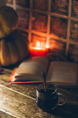 A cup of coffee in cozy rustic autumn atmosphere with the candles and a book