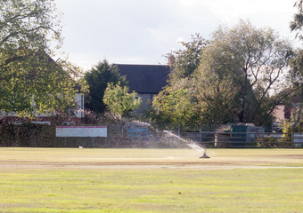 sprinkler in action water spray on cricket green field